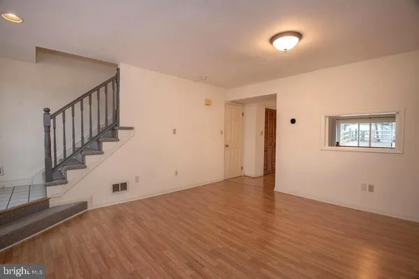 a view of an empty room with wooden floor and stairs