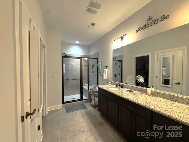 a bathroom with a granite countertop sink a mirror and shower
