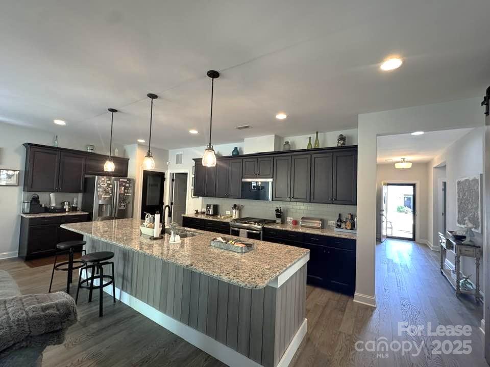 4995 Looking Glass Trail Denver, NC 28037 - Photo 5 of 32 a kitchen with stainless steel appliances granite countertop a stove top oven a sink a dining table and chairs with wooden floor