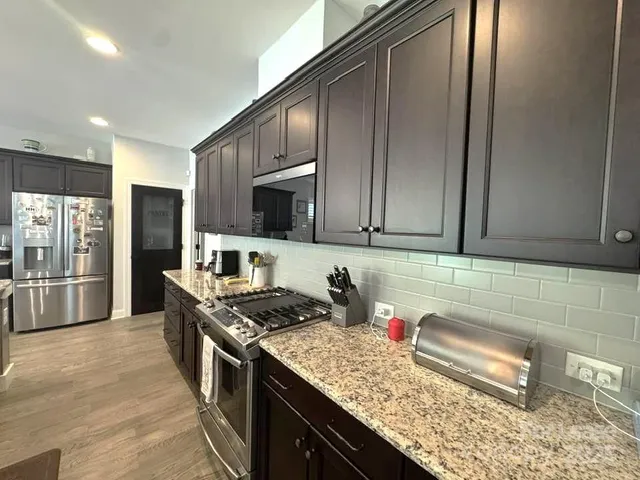 a kitchen with granite countertop a stove a sink a dining table and chairs