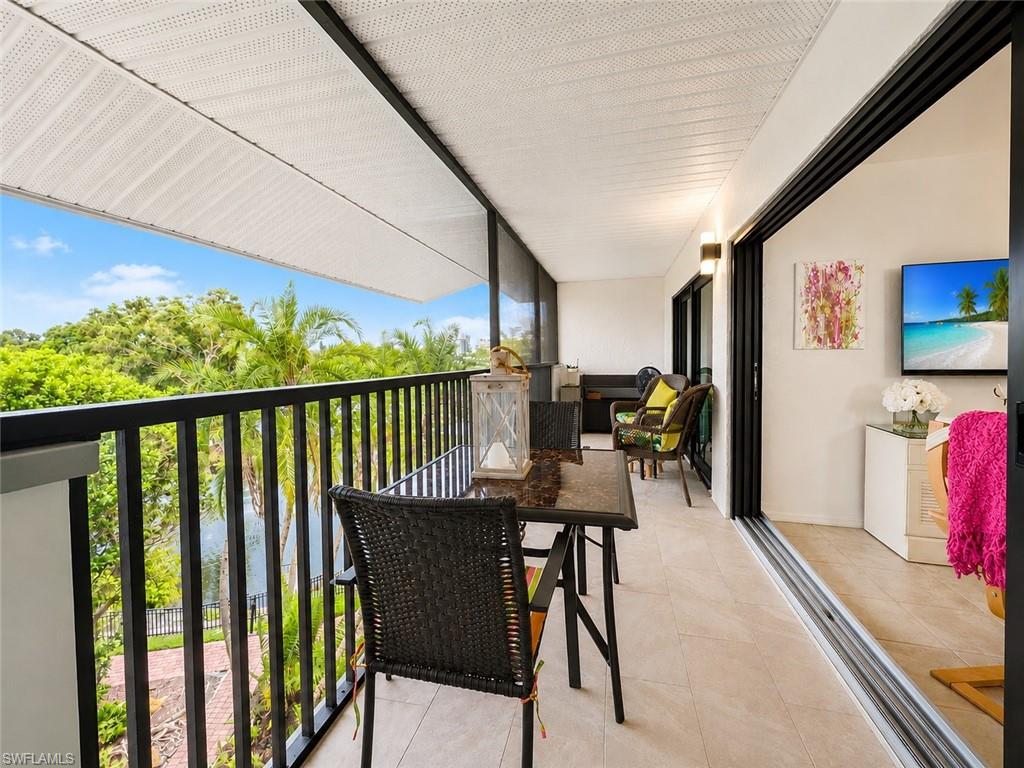 600 Neapolitan Way, Unit 449 Naples, FL 34103 - Photo 19 of 44 Expansive balcony featuring light-toned tile flooring, black metal railings, and a white perforated ceiling