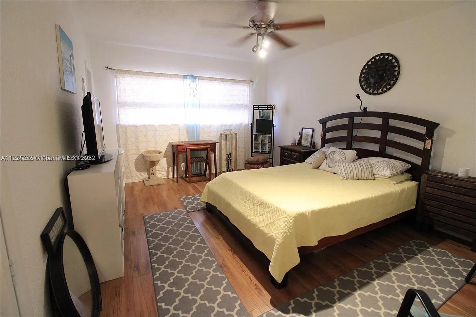 9260 Bay Harbor Terrace, Unit 22 Bay Harbor Islands, FL 33154 - Photo 17 of 24 a spacious bedroom with a bed and a chandelier