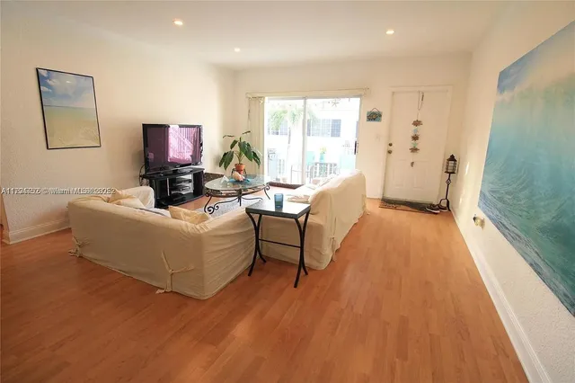 a living room with furniture a flat screen tv and a wooden floor
