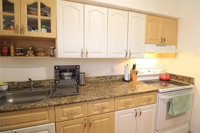 a kitchen with granite countertop a sink a stove and cabinets