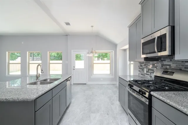 a kitchen with stainless steel appliances granite countertop a stove a sink and a microwave