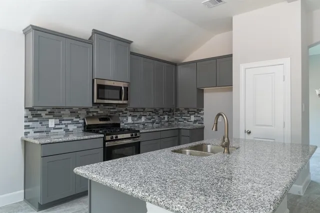 a kitchen with stainless steel appliances kitchen island granite countertop a sink stove and refrigerator