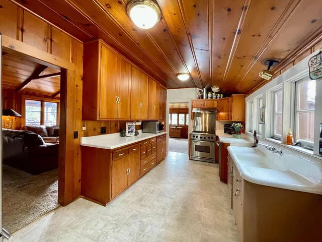 a large kitchen with stainless steel appliances wooden cabinets a stove and a sink
