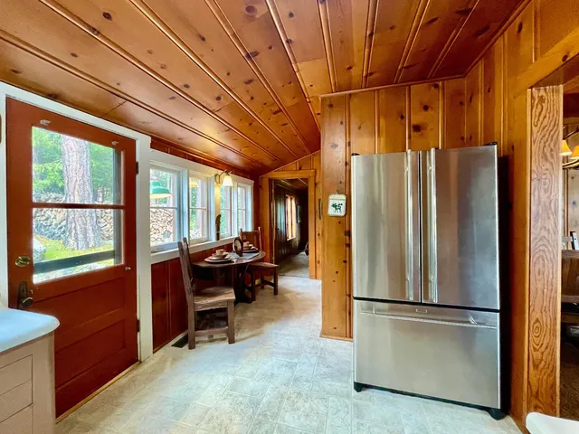 a kitchen with refrigerator a stove and a dining table next to a window