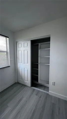 a view of an empty room with a fireplace and wooden floor