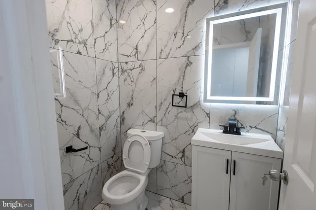 a bathroom with a granite countertop toilet sink and mirror