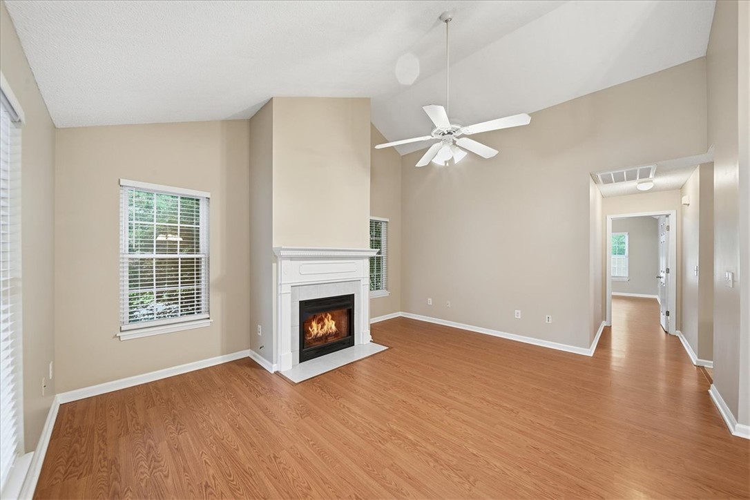 101 Grand Oak Circle Pendleton, SC 29670 - Photo 6 of 40 A generous living area features a white mantel fireplace, warm hardwood-style flooring, and a vaulted ceiling.