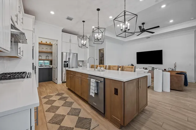 a kitchen with stainless steel appliances a stove a sink dishwasher a refrigerator and a flat screen tv