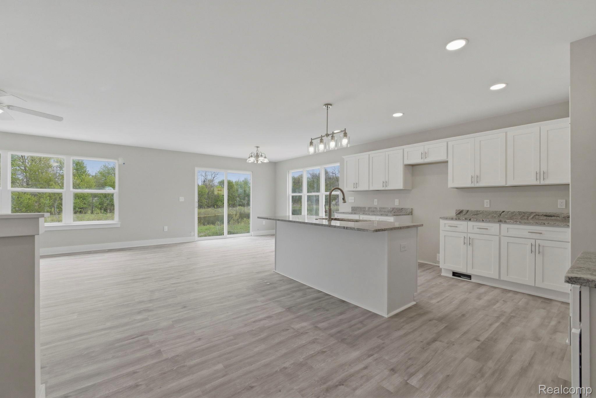 2281 Baltimore Davison, MI 48423 - Photo 6 of 26 Kitchen with a ceiling fan, white cabinetry, light stone countertops, and an island with sink