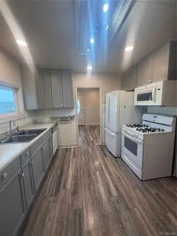 a kitchen with wooden floors and white stainless steel appliances