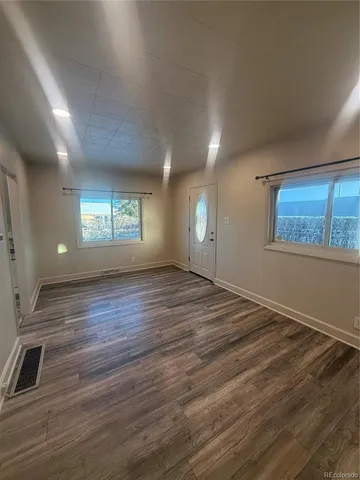 an empty room with wooden floor and windows