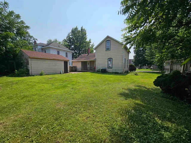 a view of a house with a yard and a large tree