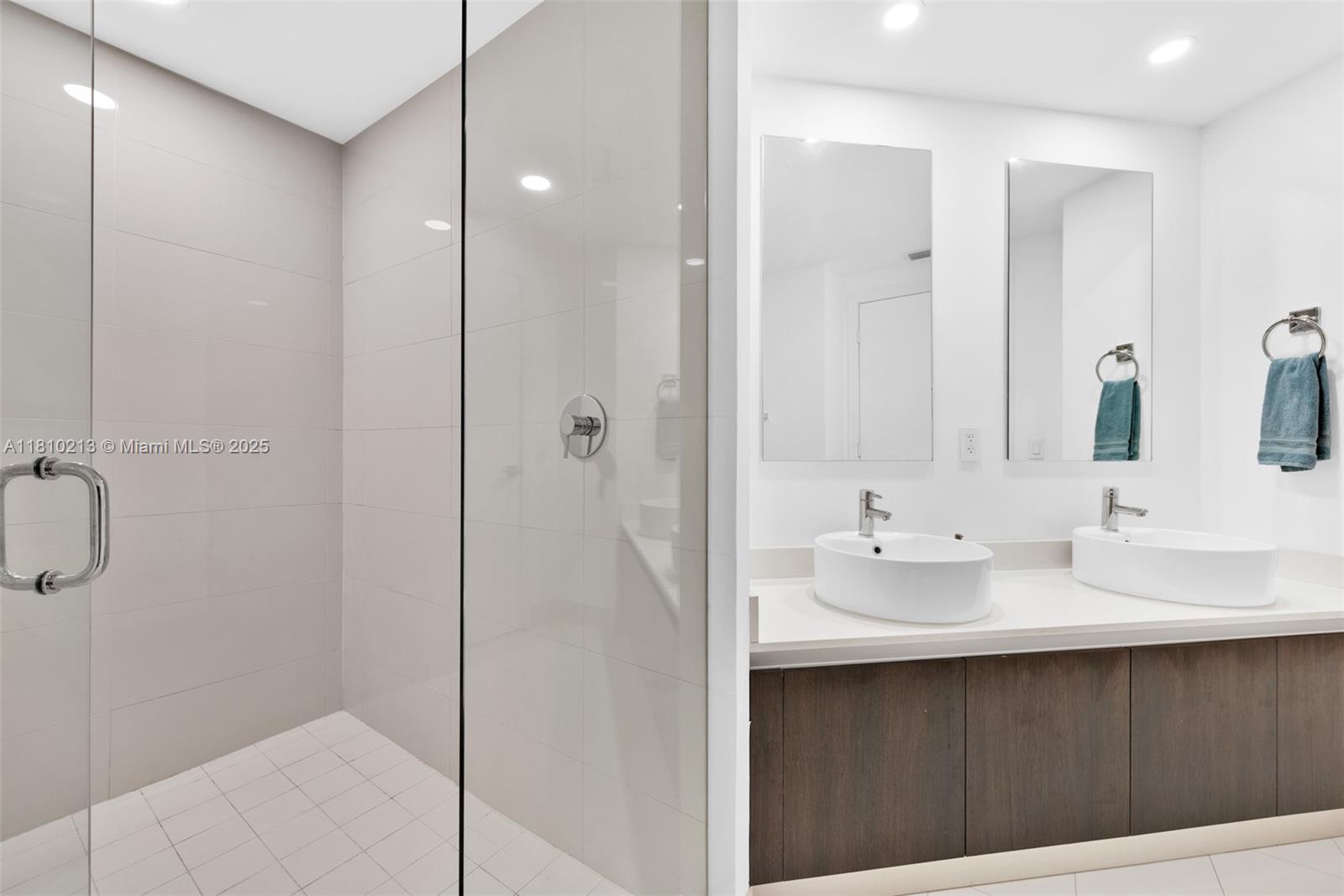 121 Northeast 34th Street, Unit L304 Miami, FL 33137 - Photo 20 of 36 a bathroom with a double vanity sink a mirror and shower