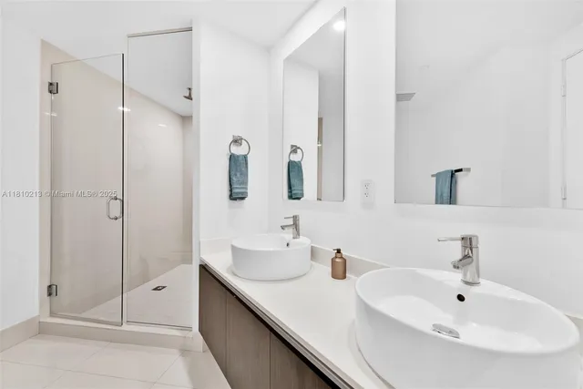a bathroom with a double vanity sink mirror and shower