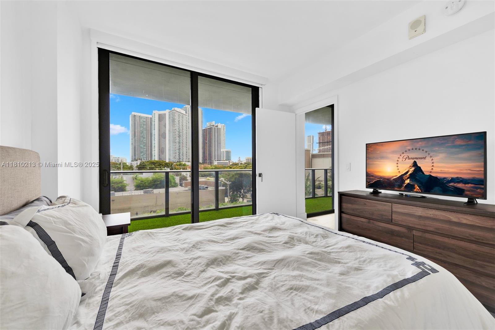 121 Northeast 34th Street, Unit L304 Miami, FL 33137 - Photo 24 of 36 a bedroom with a bed and a flat screen tv