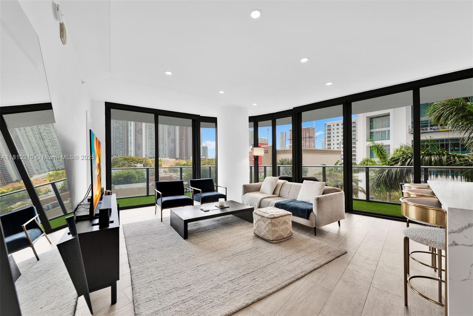 121 Northeast 34th Street, Unit L304 Miami, FL 33137 - Photo 5 of 36 a living room with furniture floor to ceiling window and flat screen tv