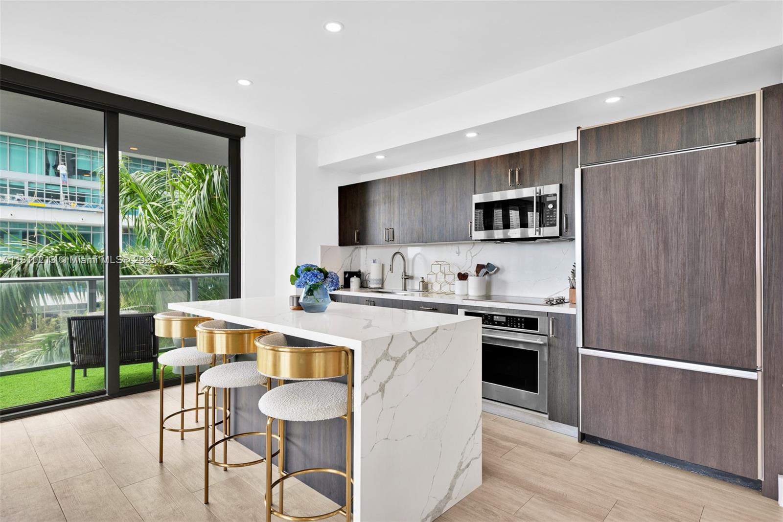 121 Northeast 34th Street, Unit L304 Miami, FL 33137 - Photo 10 of 36 a large kitchen with kitchen island a large window in it and stainless steel appliances