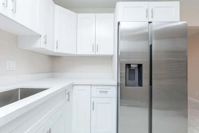 a kitchen with a refrigerator and white cabinets