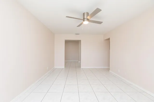 an empty room with white walls and ceiling fan