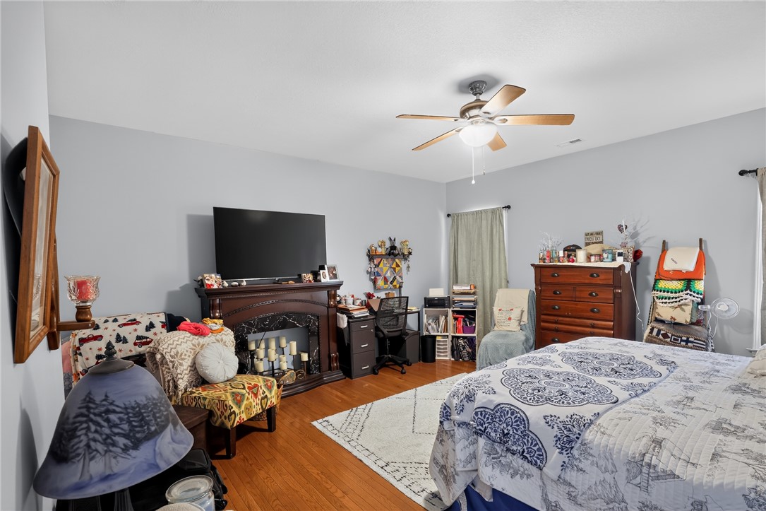 144 Elliott Circle Anderson, SC 29621 - Photo 19 of 30 Hardwood floors and a ceiling fan enhance this cozy bedroom with an elegant fireplace focal point.