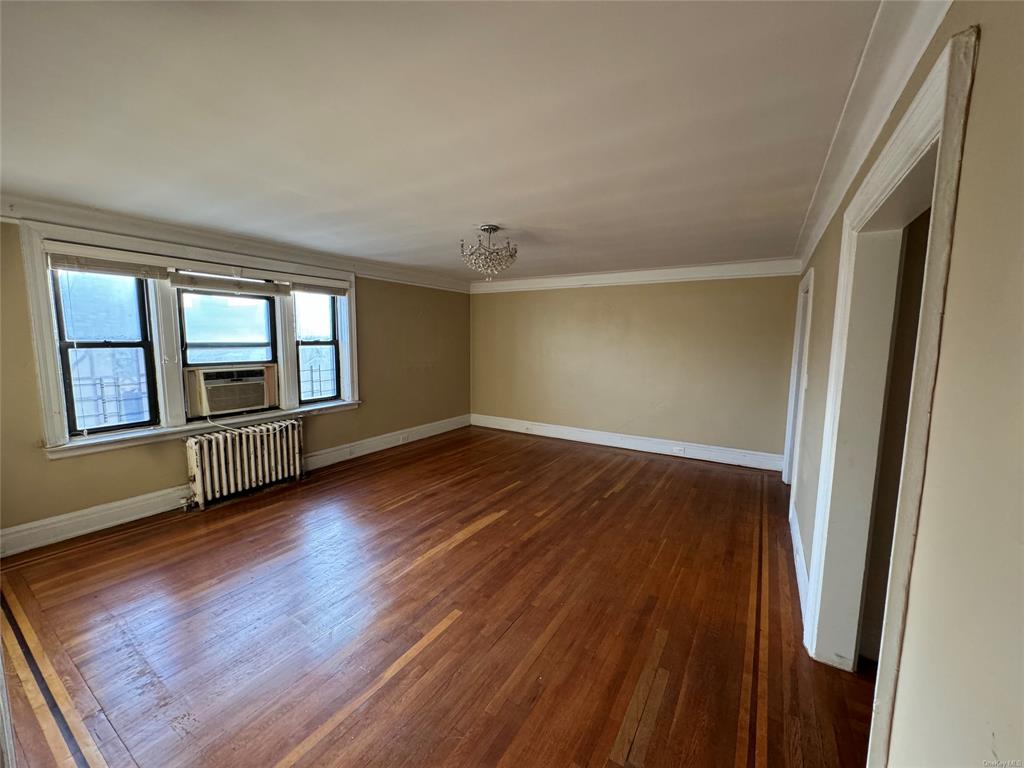 42 Pondfield Road, Unit 6C Bronxville, NY 10708 - Photo 11 of 21 Unfurnished room featuring dark hardwood / wood-style flooring, radiator, cooling unit, crown molding, and a notable chandelier