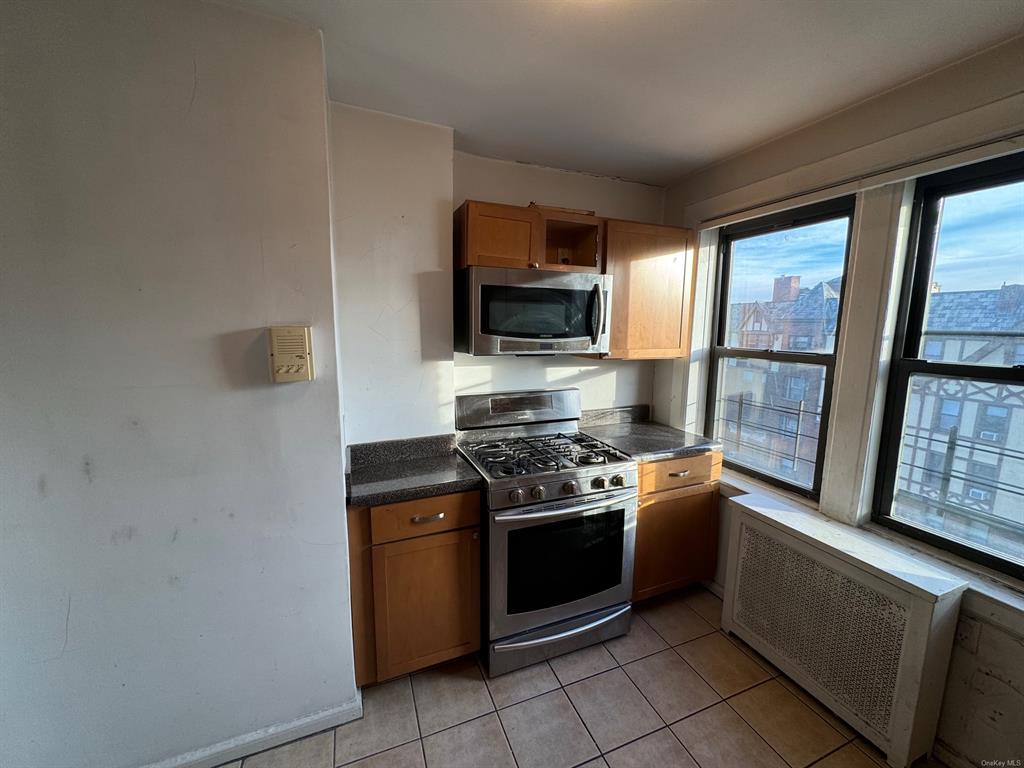 42 Pondfield Road, Unit 6C Bronxville, NY 10708 - Photo 13 of 21 Kitchen with radiator heating unit, light tile patterned floors, and appliances with stainless steel finishes