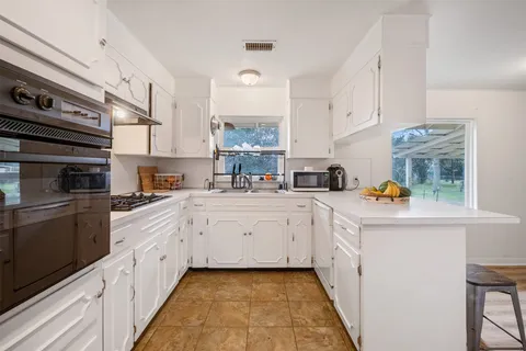 a kitchen with white cabinets and window