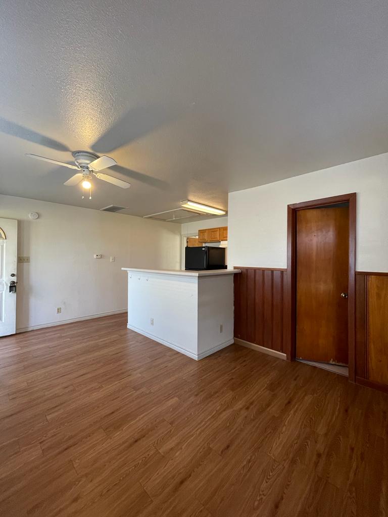 108 Austin Street, Unit B Kyle, TX 78640 - Photo 4 of 14 A versatile living area features warm wood-look flooring and a functional breakfast bar connecting to the kitchen.
