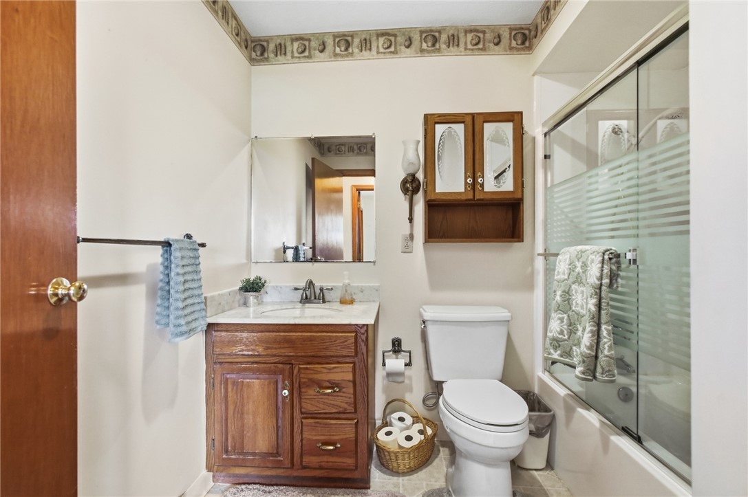 6718 Old Columbus Road South Vienna, OH 45369 - Photo 23 of 33 This bathroom features a sleek shower with frosted glass, a classic toilet, and a charming wooden vanity.