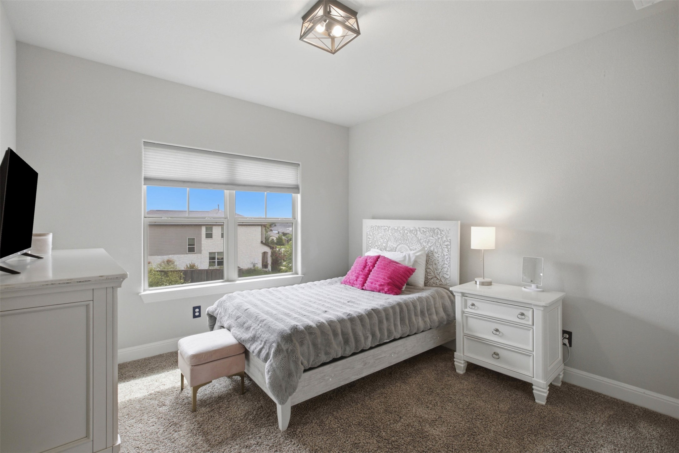1113 Modoc Way Kyle, TX 78640 - Photo 24 of 34 A well-lit room with plush carpeting, a single window offering a neighborhood view, and a modern ceiling fixture.