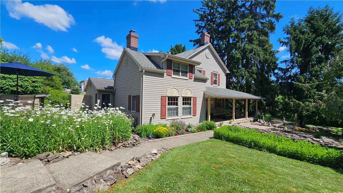 585 Buttermilk Road Hellertown, PA 18055 - Photo 40 of 82 A charming exterior with vinyl siding and red shutters, complemented by a welcoming front porch and vibrant garden beds.