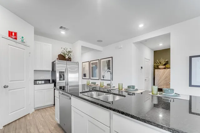 a kitchen with granite countertop a sink stainless steel appliances and white cabinets