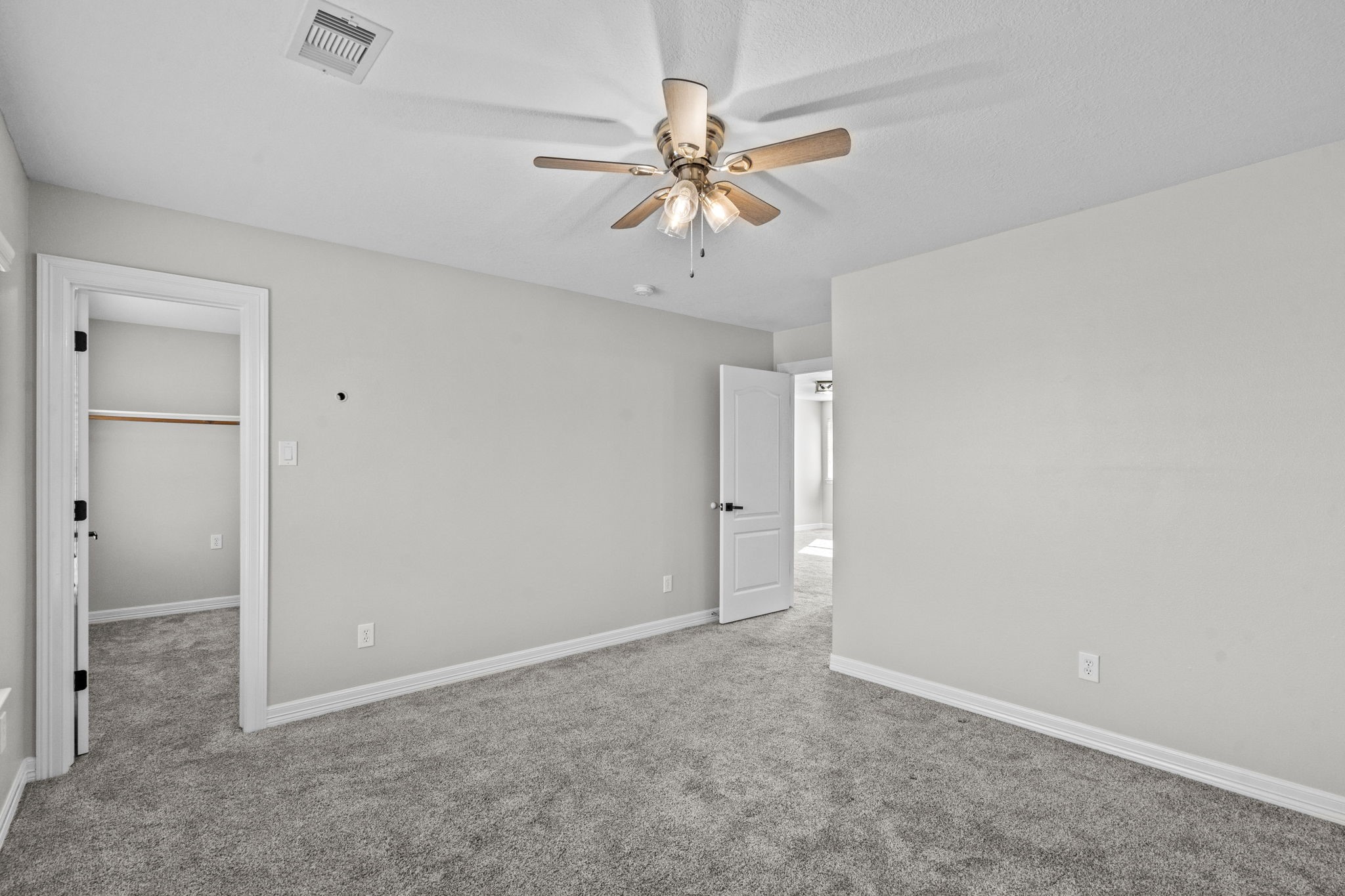 2730 Lawrence Road Kemah, TX 77565 - Photo 35 of 46 This room features neutral walls, a ceiling fan, and plush carpet. It includes a door leading to a spacious closet and another to a bright adjacent room, creating a cozy and functional space.