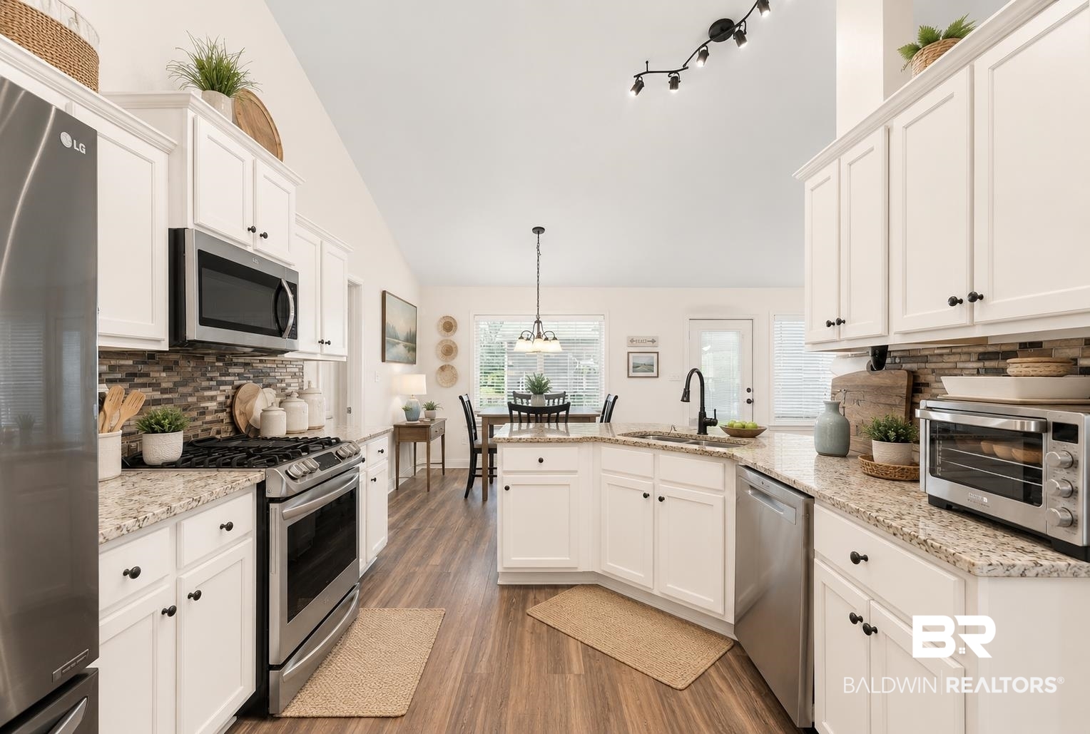 562 Vestige Mews Foley, AL 36535 - Photo 18 of 54 AI Edited Image: Open-concept kitchen featuring vaulted ceilings, white cabinetry, stainless steel appliances, granite countertops, and wood-finish flooring