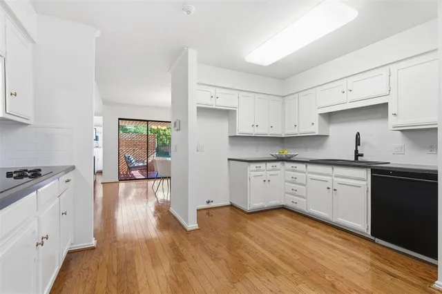 a kitchen with granite countertop a stove top oven a sink dishwasher and white cabinets with wooden floor