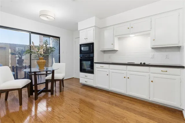 a kitchen with white cabinets and wooden floor