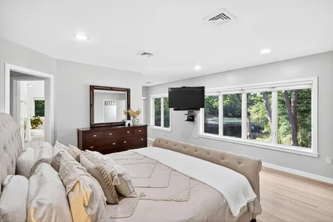 a bedroom with a large bed and a flat tv screen on dresser