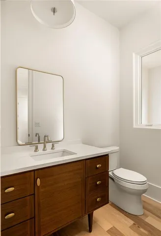 a bathroom with a toilet a sink a mirror and vanity