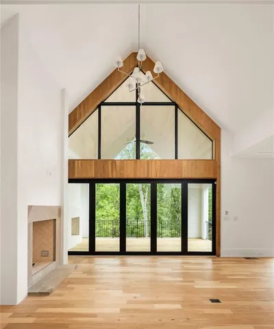 an empty room with wooden floor fireplace and windows