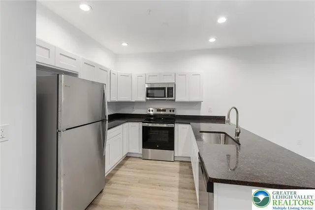 a kitchen with granite countertop a refrigerator and a sink