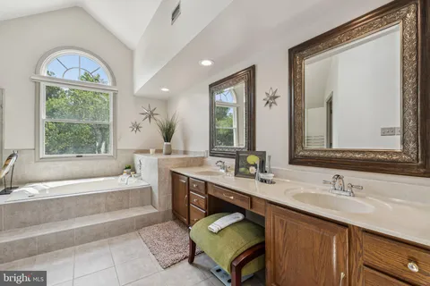 a bathroom with a tub a sink and a large mirror