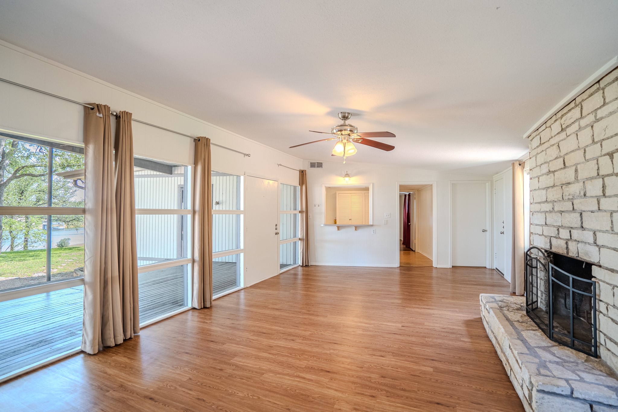 16013 Edwards Drive Austin, TX 78734 - Photo 6 of 18 A welcoming living area boasts durable laminate flooring, a whitewashed brick fireplace, and generous windows overlooking the deck.