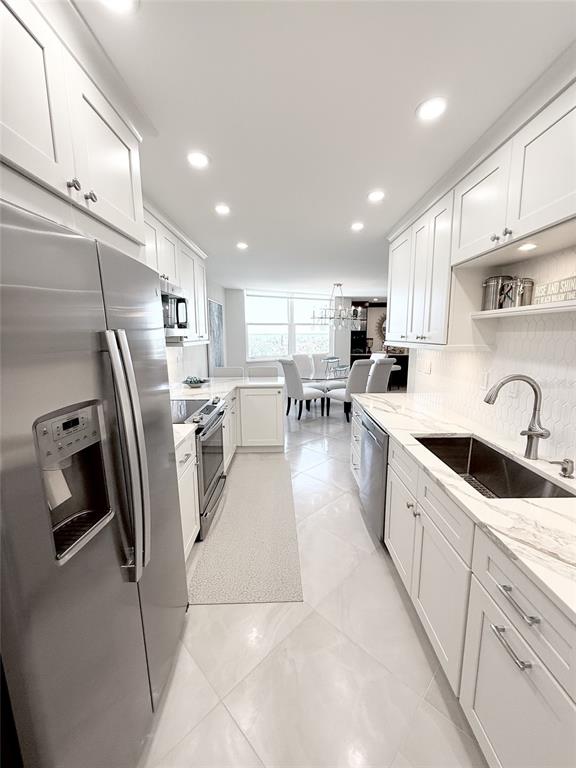 1050 Longboat Club Road, Unit 803 Longboat Key, FL 34228 - Photo 16 of 39 a kitchen with stainless steel appliances granite countertop a refrigerator a sink a stove and white cabinets with wooden floor