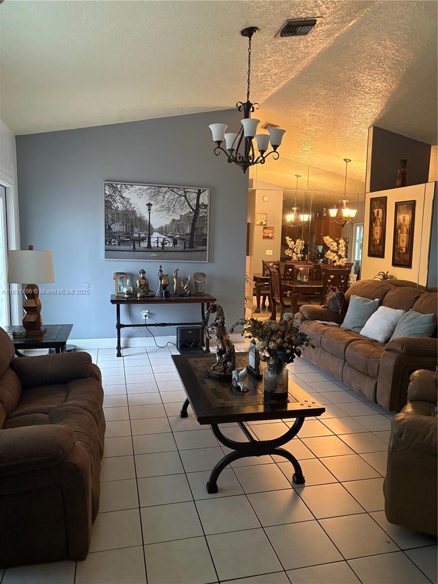 12601 Southwest 268th Street Homestead, FL 33032 - Photo 4 of 17 a living room with furniture a chandelier and a flat screen tv