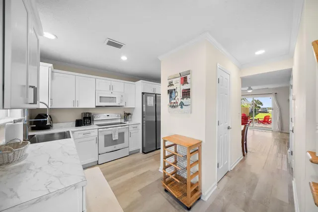 a view of a white house with a small yard and wooden fence