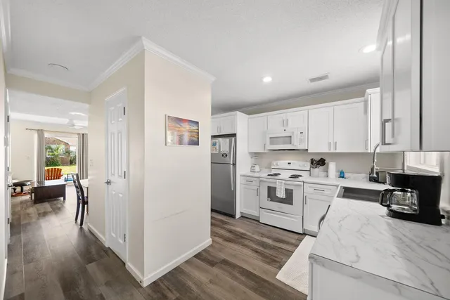 a view of a white house with a big yard and potted plants